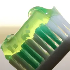 Cepillo de dientes con pasta verde, destacando los beneficios del fluor en los dientes para una sonrisa sana y protegida.