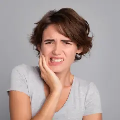 Mujer con dolor de muelas, quizás por no lavarse los dientes.