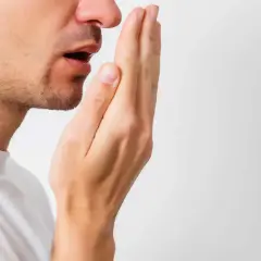 Hombre revisando su aliento, buscando soluciones para la halitosis.
