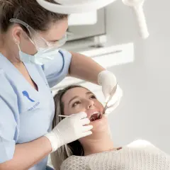Dentista realiza limpieza de dientes a paciente.