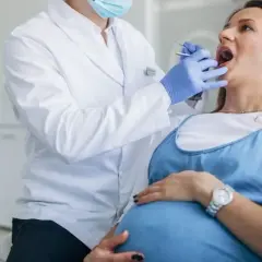 Dentista examina la boca de una mujer embarazada, cuidando sus encías inflamadas durante el embarazo.