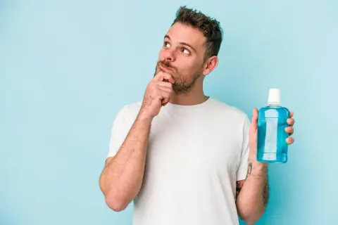 Hombre pensativo con enjuague bucal, ¿será la solución para una infección?