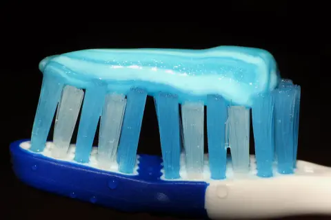 Pasta de dientes azul y blanca sobre cerdas de cepillo, lista para una limpieza. ¿Cómo lavarse los dientes sin cepillo? ¡Imposible!
