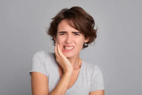 Mujer con dolor de muelas, quizás por no lavarse los dientes.