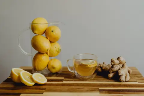 Jarra con limones, taza de té con rodaja de limón y jengibre. Una bebida refrescante para combatir el aliento ácido.