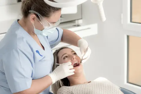 Dentista realiza limpieza de dientes a paciente.