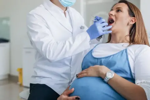 Dentista examina la boca de una mujer embarazada, cuidando sus encías inflamadas durante el embarazo.