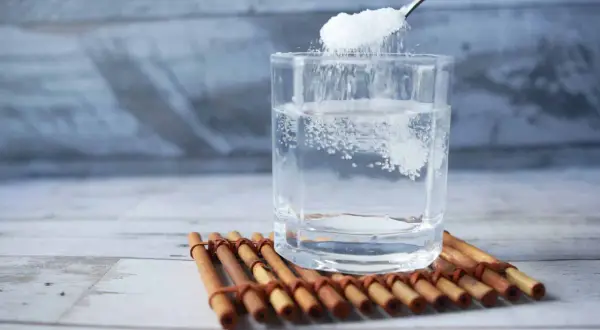 Cuchara añade sal a un vaso de agua, remedio casero para aliviar las encías inflamadas.