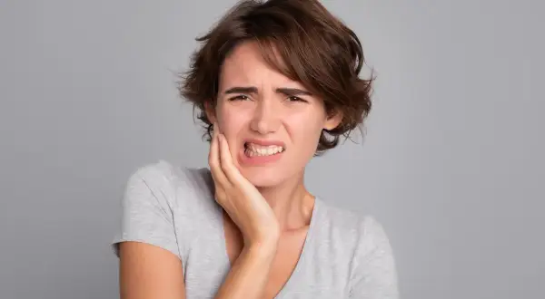 Mujer con dolor de muelas, quizás por no lavarse los dientes.