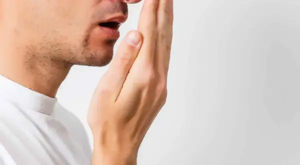 Hombre revisando su aliento, buscando soluciones para la halitosis.