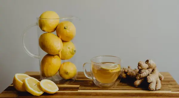 Jarra con limones, taza de té con rodaja de limón y jengibre. Una bebida refrescante para combatir el aliento ácido.