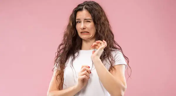 Mujer con expresión de desagrado, como si tuviera la boca salada. Podría ser por algo que comió o por deshidratación.
