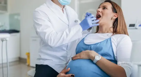 Dentista examina la boca de una mujer embarazada, cuidando sus encías inflamadas durante el embarazo.