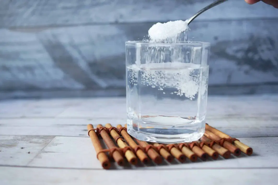 Cuchara añade sal a un vaso de agua, remedio casero para aliviar las encías inflamadas.