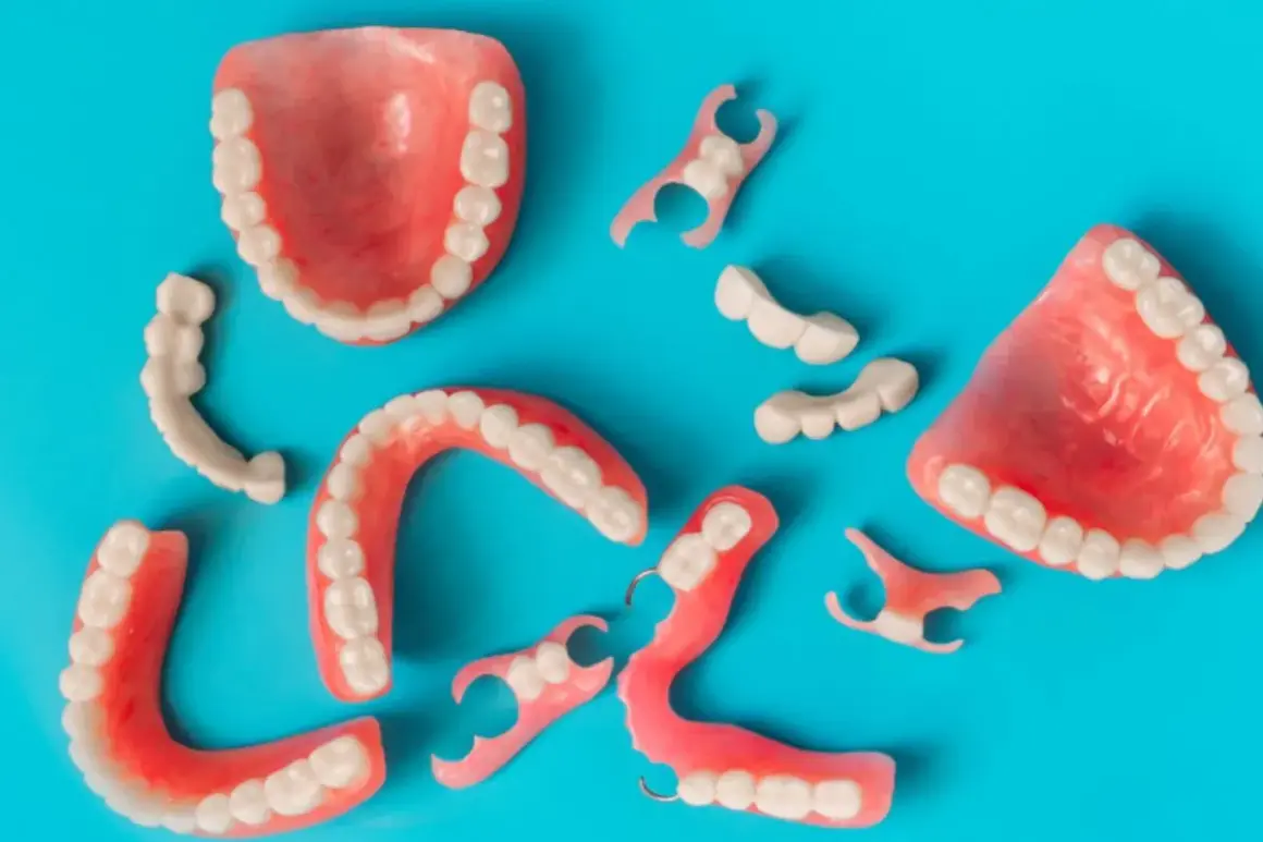 Variedad de protesicos dentales, incluyendo dentaduras completas y parciales, esparcidos sobre un fondo azul.