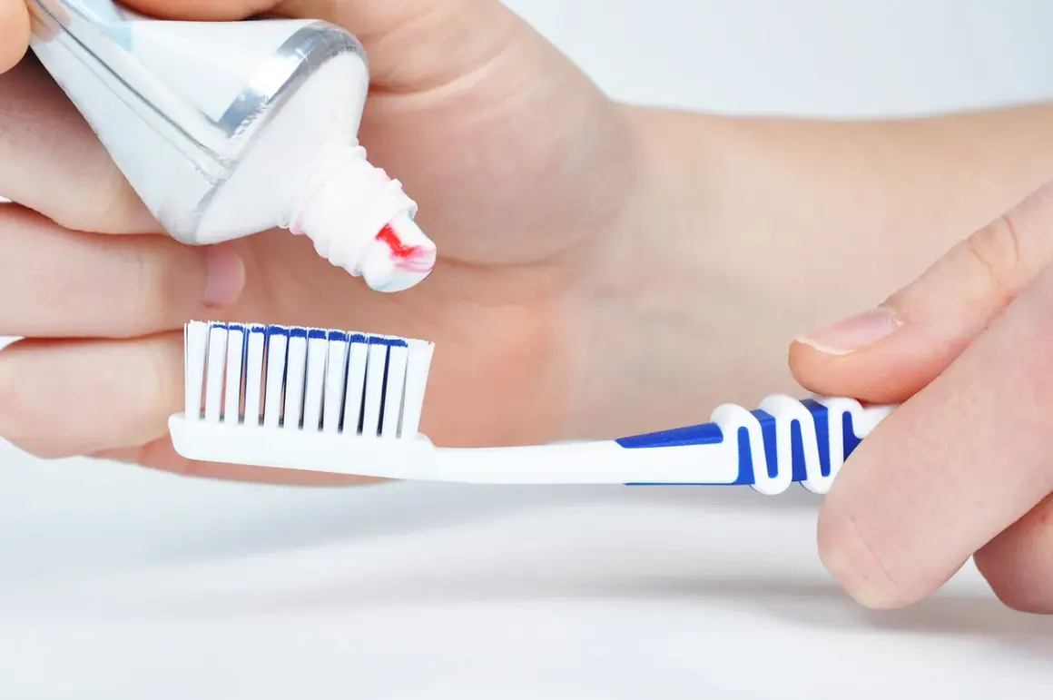 Manos aplican pasta de dientes a un cepillo. La pasta de dientes está hecha de ingredientes que limpian y protegen.