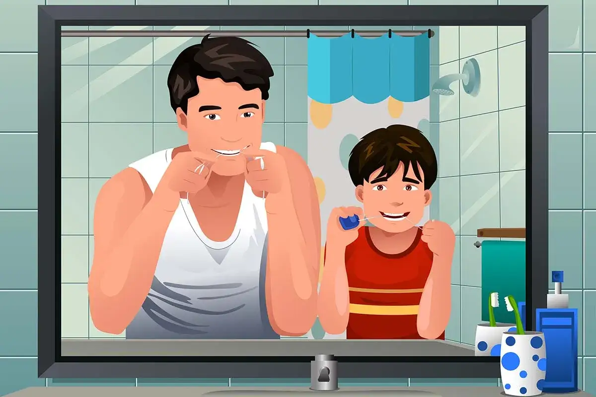 Padre e hijo se limpian los dientes con hilo dental, un ejemplo de prevenci&oacute;n de caries.