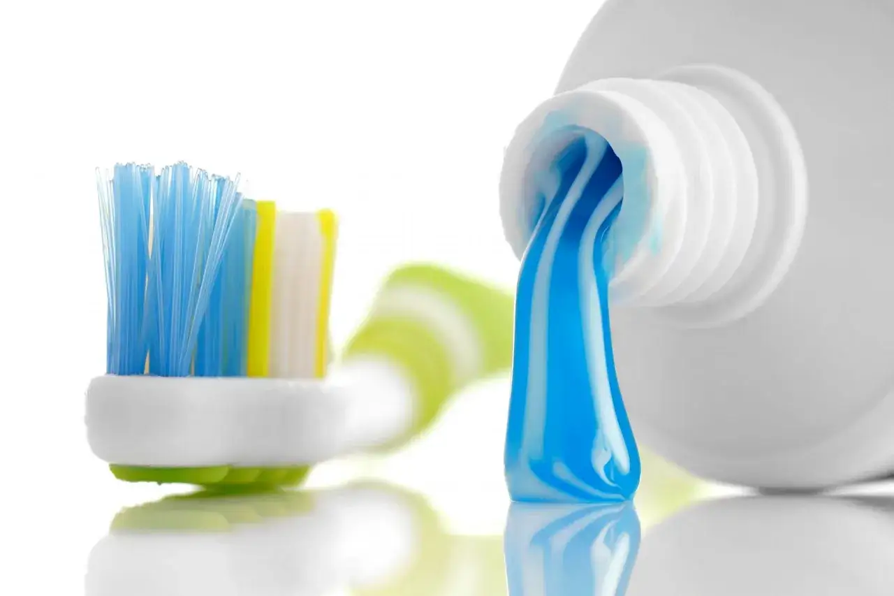 Cepillo de dientes con pasta azul y blanca lista para usar. Un sorbo de agua después de lavarse los dientes refresca.