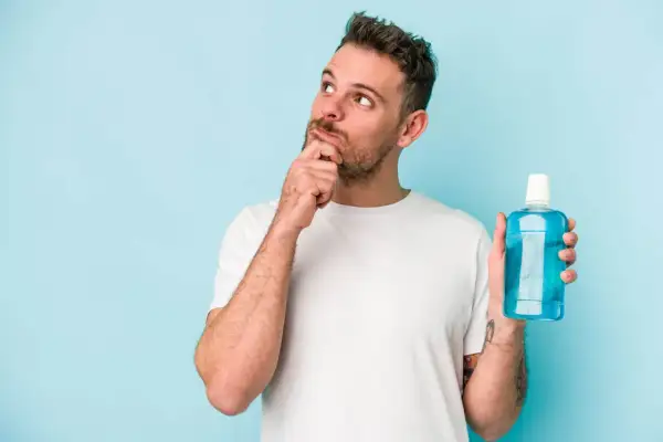 Hombre pensativo con enjuague bucal, ¿será la solución para una infección?