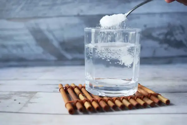 Cuchara añade sal a un vaso de agua, remedio casero para aliviar las encías inflamadas.