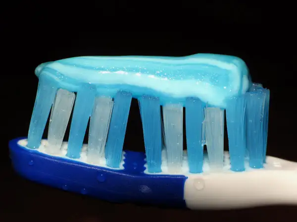 Pasta de dientes azul y blanca sobre cerdas de cepillo, lista para una limpieza. ¿Cómo lavarse los dientes sin cepillo? ¡Imposible!