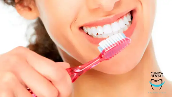 Una mujer se cepilla los dientes con una sonrisa radiante. Con un cepillado diario, se puede quitar una caries y mantener una boca sana.