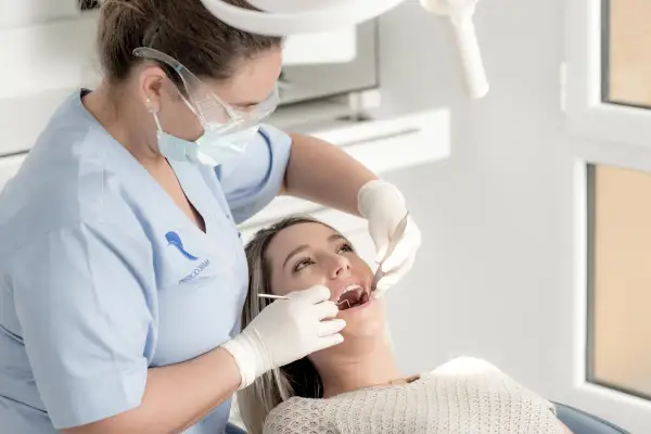 Dentista realiza limpieza de dientes a paciente.
