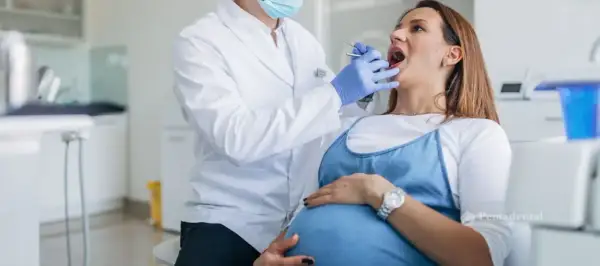 Dentista examina la boca de una mujer embarazada, cuidando sus encías inflamadas durante el embarazo.